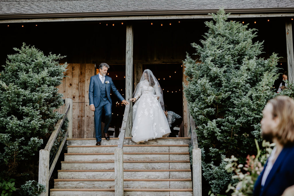 bride and father walking down aisle at barn wedding